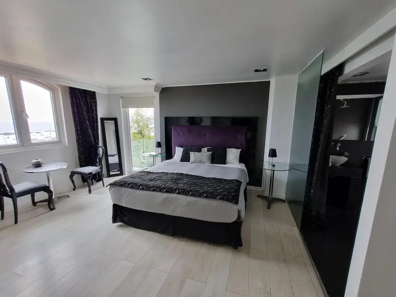 Une chambre spacieuse avec un grand lit et un coin repas près de la fenêtre.