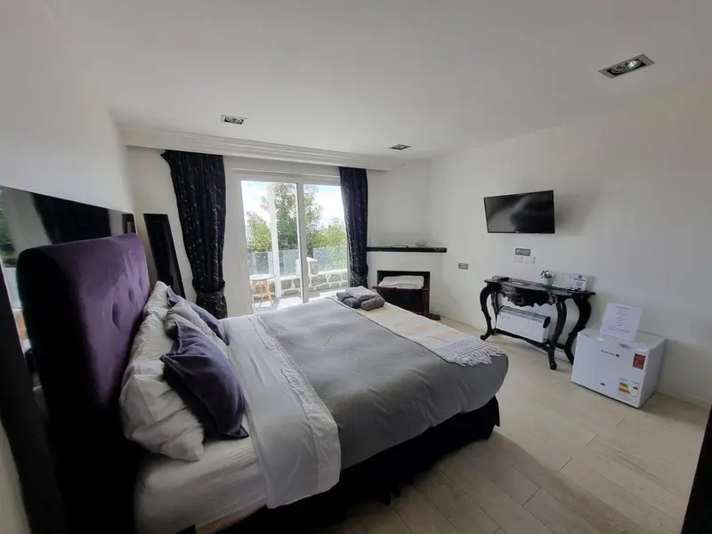 Une chambre lumineuse avec un grand lit et une télévision murale.