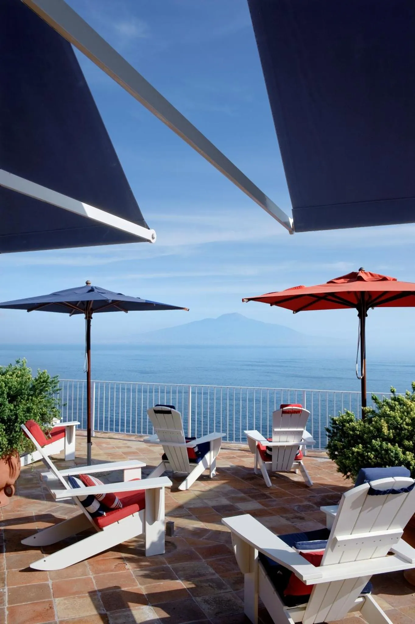 Terrasse ombragée avec transats et vue sur la mer.