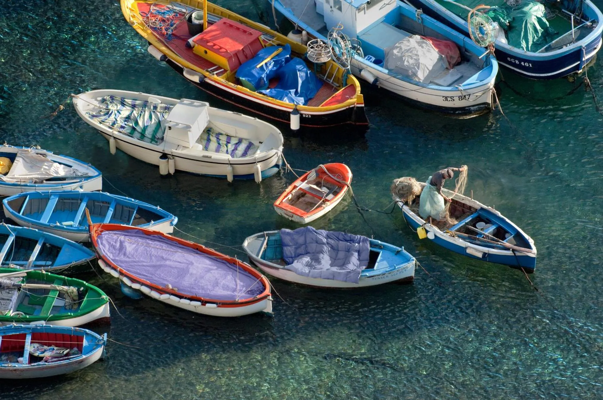 Des bateaux colorés sont amarrés dans une eau turquoise.