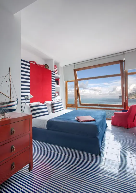 Une chambre lumineuse avec un lit fait et une vue sur la mer.