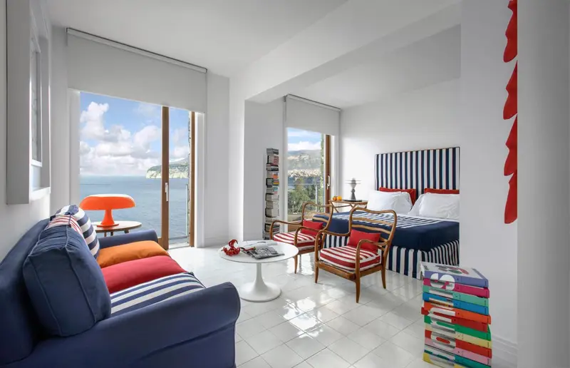 Une chambre lumineuse avec un canapé coloré et une vue sur la mer.