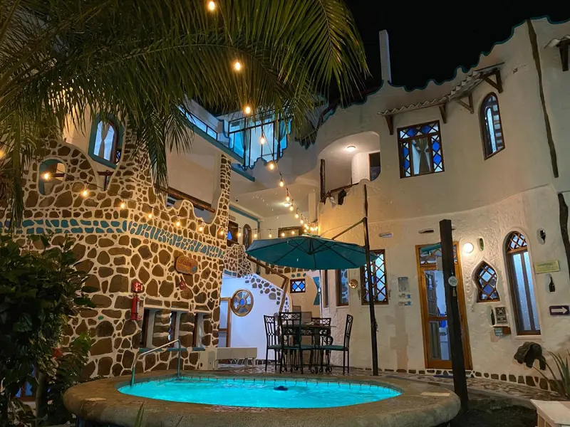 Une cour intérieure illuminée avec une petite piscine et des tables.