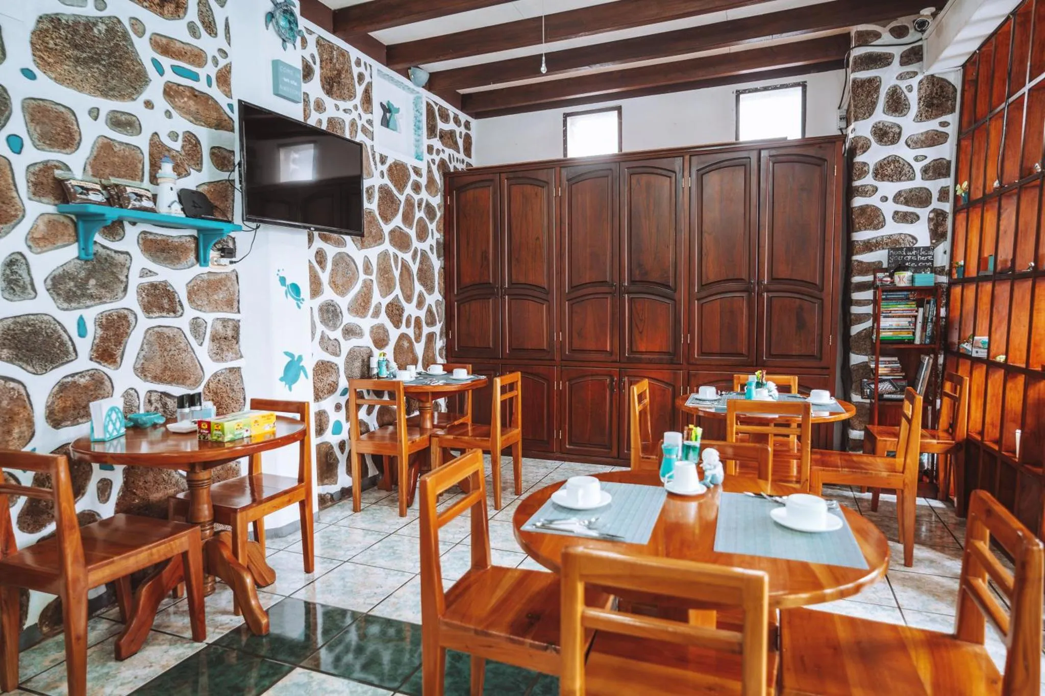 Une salle à manger lumineuse avec des tables en bois et des murs en pierre.