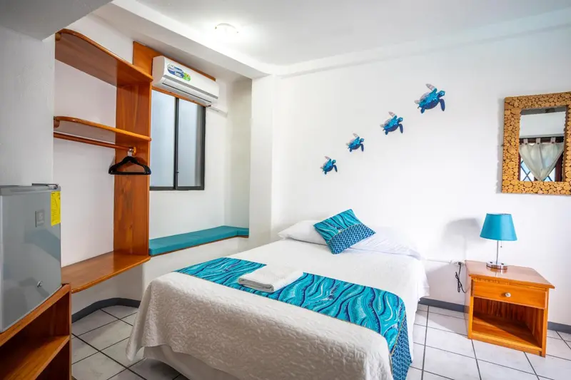 Une chambre lumineuse avec un lit recouvert d'une courtepointe bleue et turquoise.