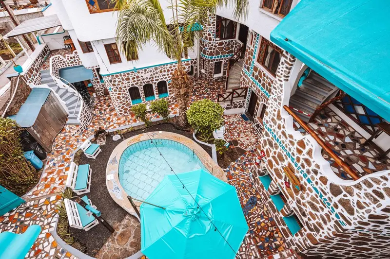 Vue aérienne d'une cour intérieure avec une piscine et des transats turquoise.