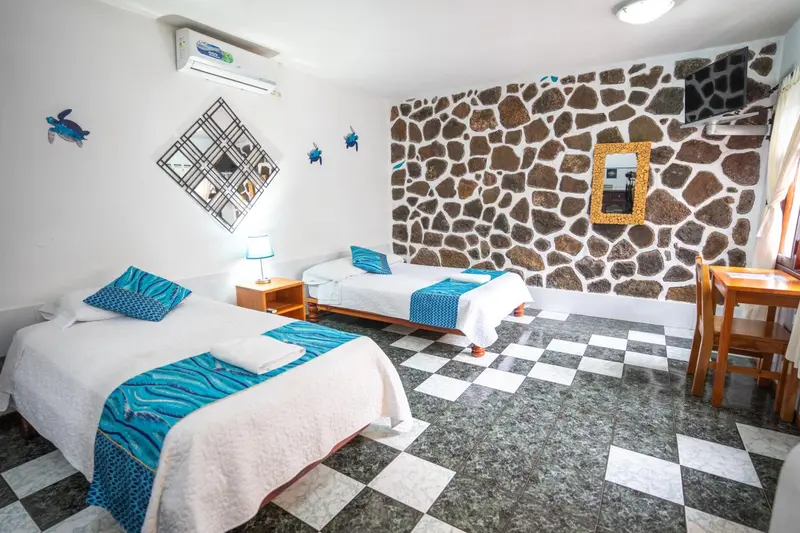 Une chambre lumineuse avec deux lits simples et un mur en pierre.