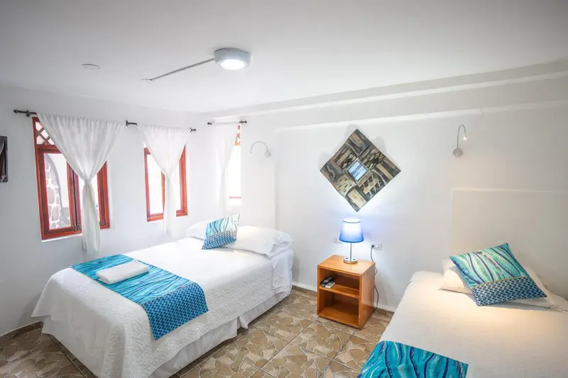 Chambre lumineuse avec deux lits simples et une décoration murale.