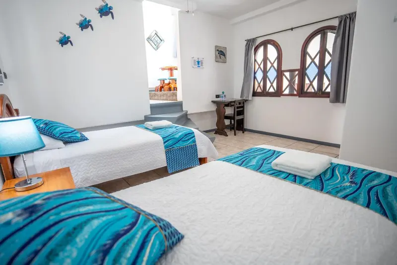 Chambre lumineuse avec deux lits simples et une décoration marine.