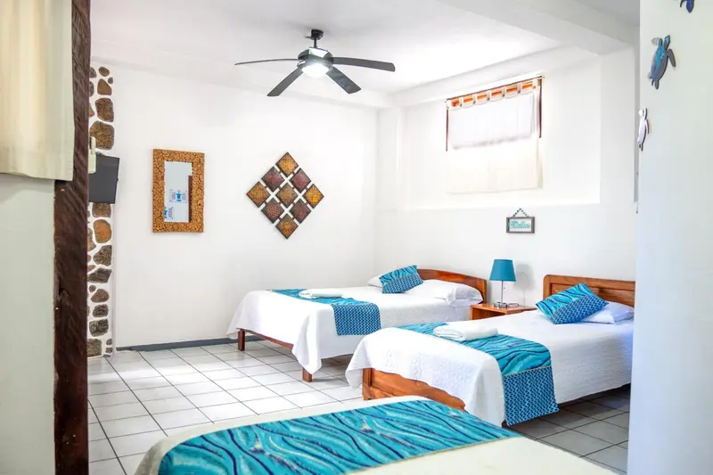 Une chambre lumineuse avec deux lits simples et une décoration murale colorée.