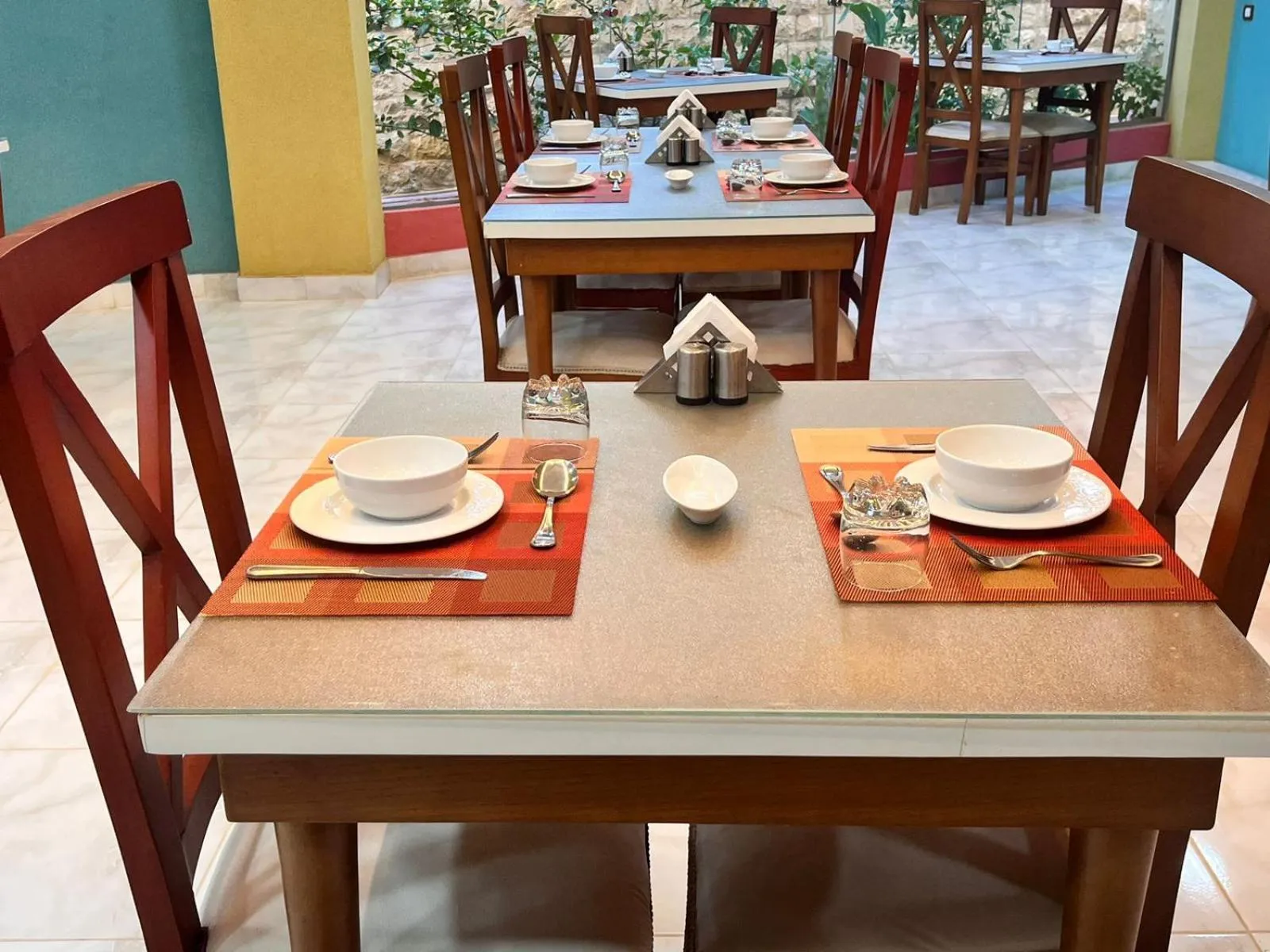 Une table est mise pour le repas avec une assiette, des couverts et une tasse.