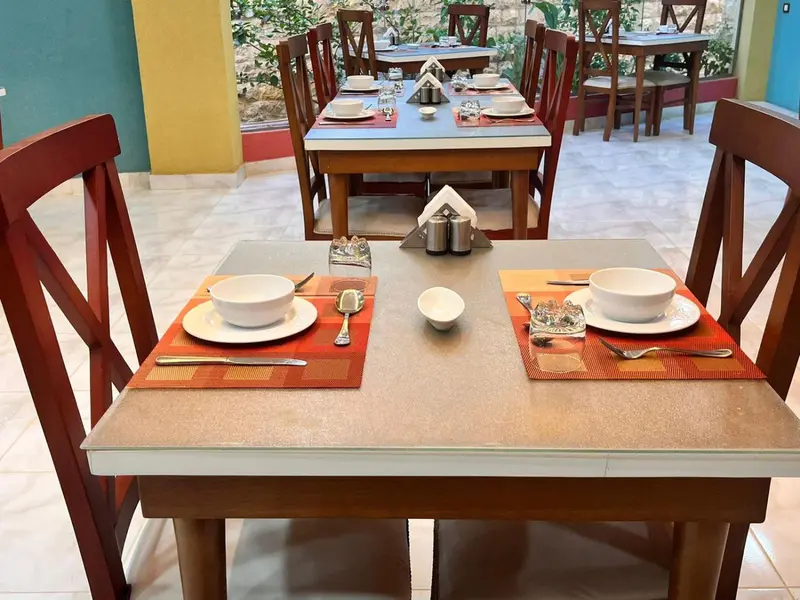 Une table est mise pour le repas avec une assiette, des couverts et une tasse.