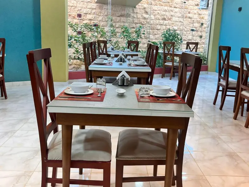 Une salle de restaurant lumineuse avec des tables dressées pour le service.