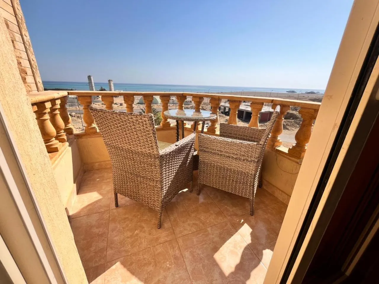 Terrasse carrelée avec mobilier en rotin et vue sur la mer.