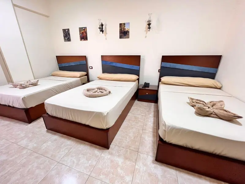 Trois lits simples dans une chambre lumineuse et décorée.