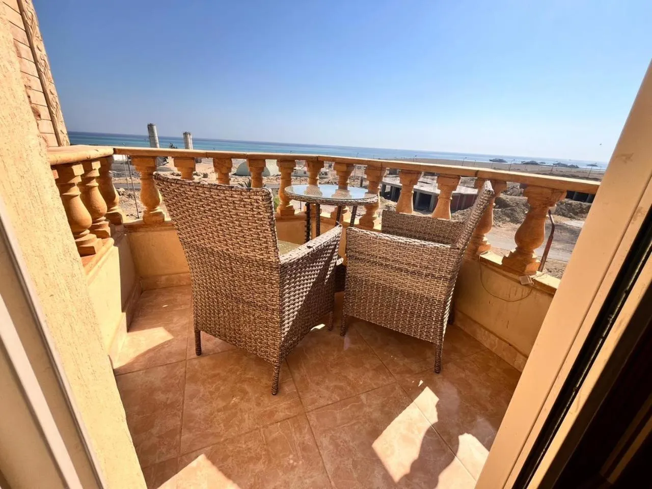 Terrasse avec mobilier en osier donnant sur la mer.
