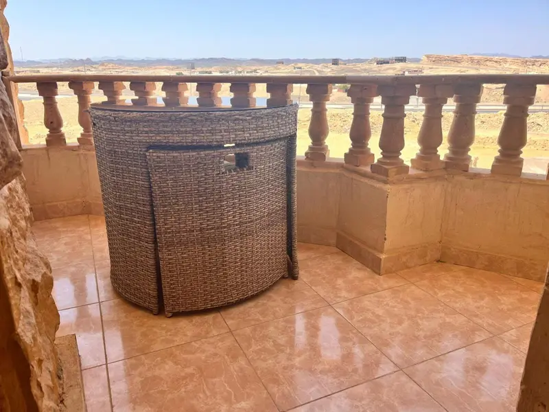 Terrasse carrelée avec mobilier en osier et vue sur un paysage désertique.