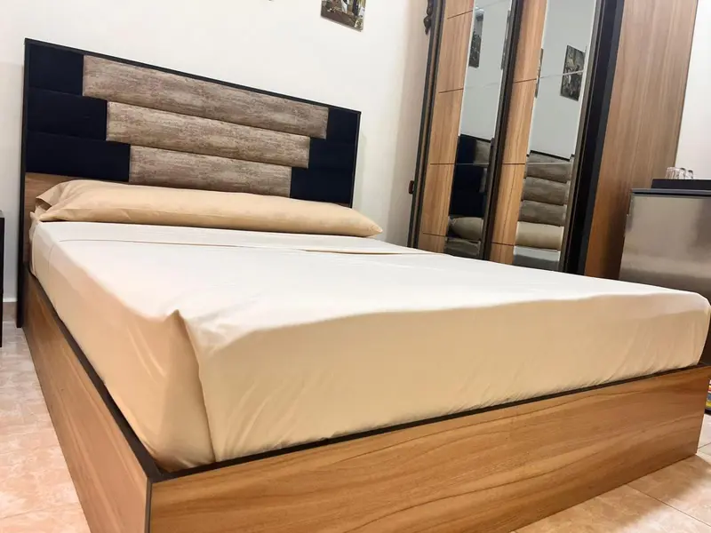 Une chambre avec un grand lit recouvert d'une courtepointe claire et d'oreillers.