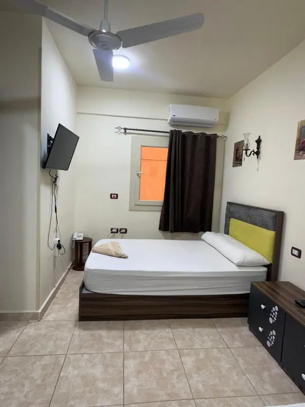 Une chambre lumineuse avec un lit simple et un ventilateur au plafond.