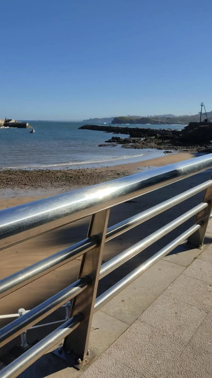Une plage de sable fin bordée d'une promenade ensoleillée.