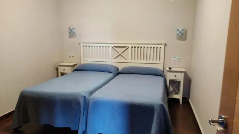 Une chambre avec deux lits simples recouverts d'une couverture bleue.