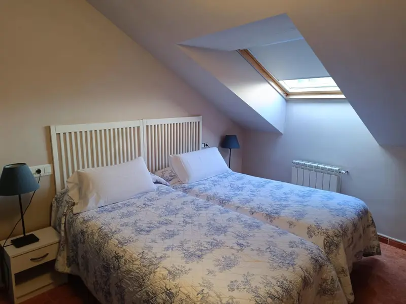 Une chambre mansardée avec un lit recouvert d'une couette à motifs.