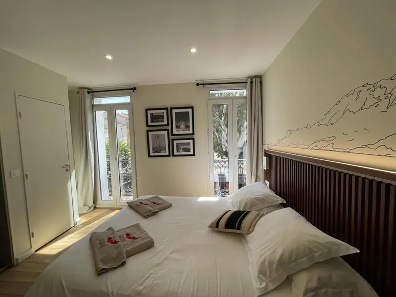 Une chambre lumineuse avec un grand lit et un accès à un balcon.