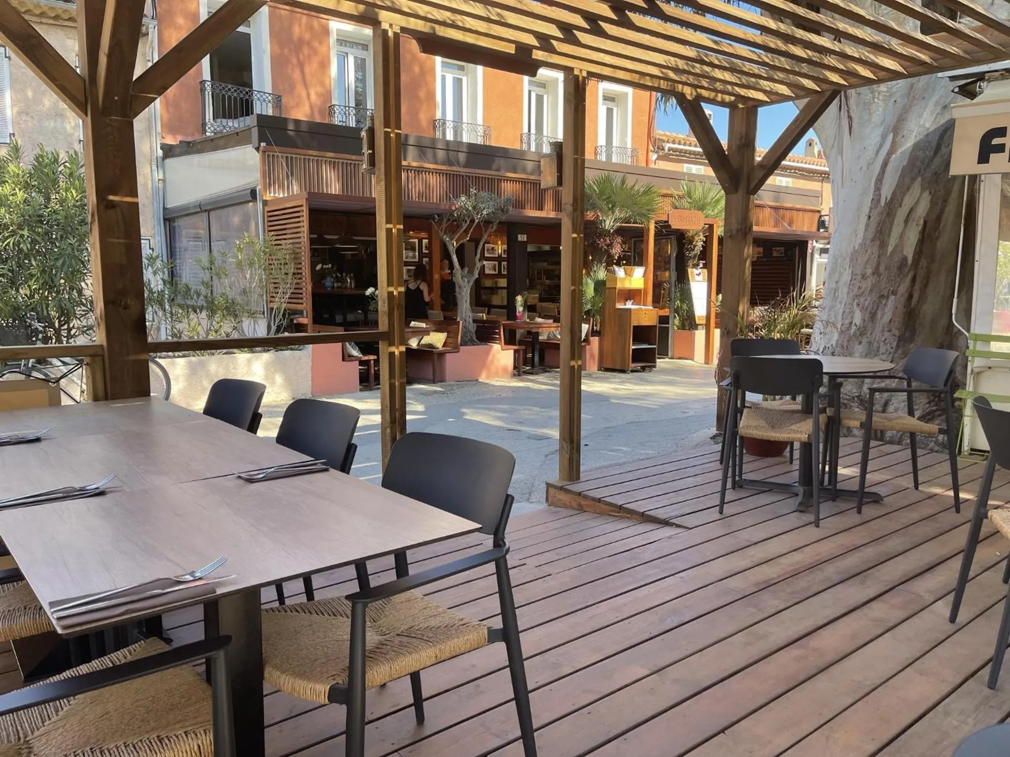 Terrasse ombragée avec tables et chaises préparées pour le service.
