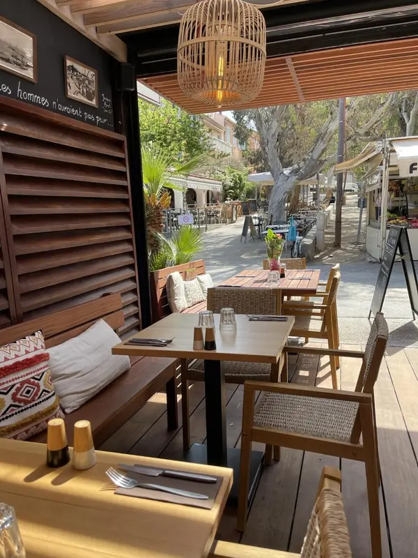 Terrasse ombragée avec tables et chaises en bois, prête pour le service.