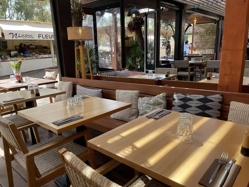 Tables en bois et chaises en rotin dans une salle à manger lumineuse.