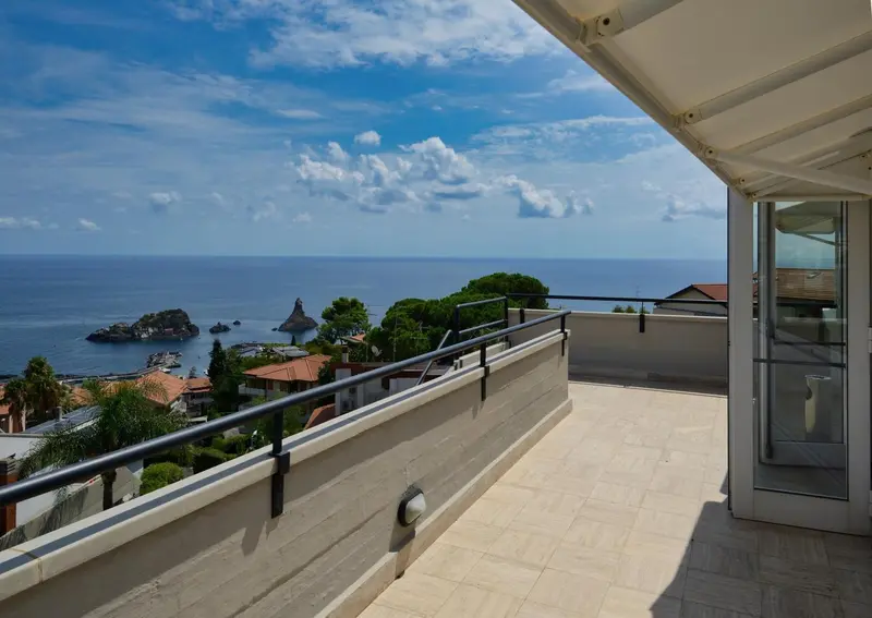 Terrasse carrelée avec vue sur la mer et la côte rocheuse.