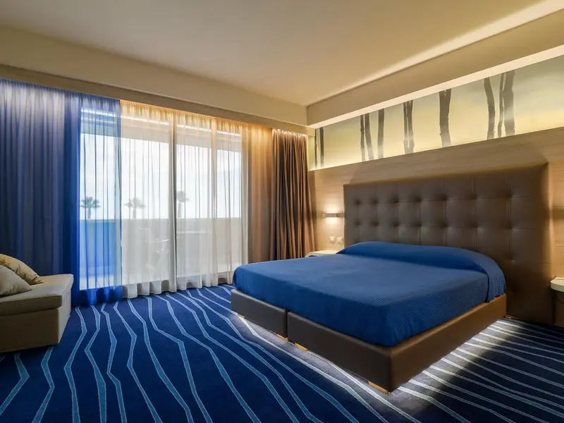 Chambre lumineuse avec un grand lit et vue sur la mer.