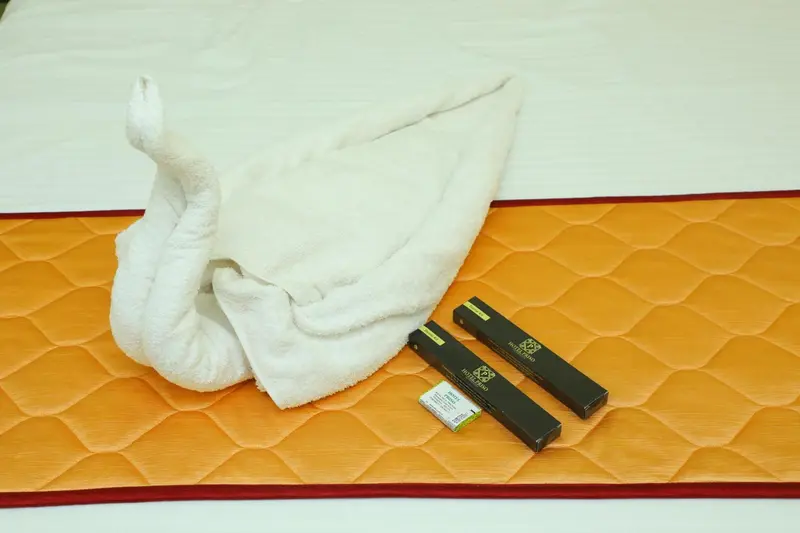 Un lit recouvert d'une courtepointe orange et orné de serviettes pliées en forme d'animaux.