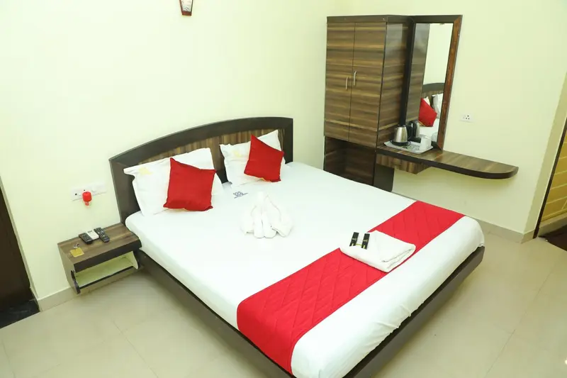 Une chambre lumineuse avec un grand lit recouvert d'une courtepointe blanche et de coussins rouges.