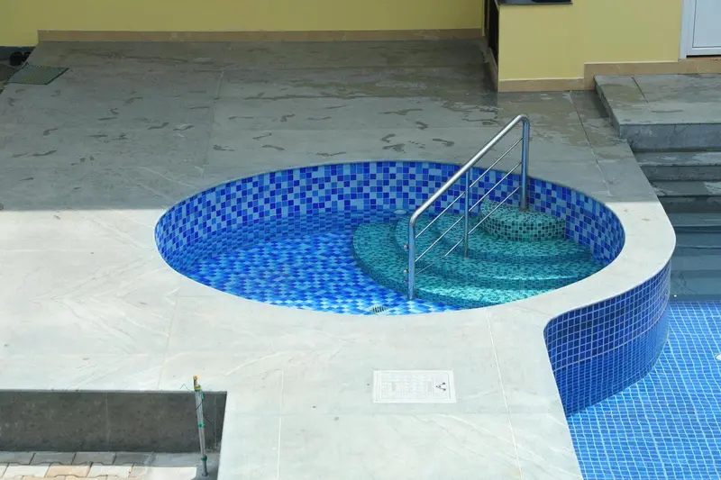 Un jacuzzi extérieur circulaire est intégré à une terrasse carrelée.