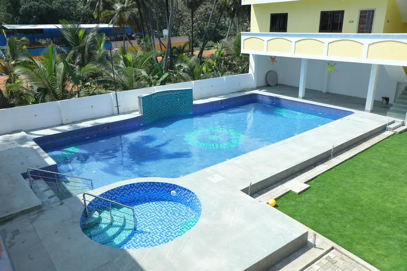 Une piscine rectangulaire avec un espace de détente intégré et une cascade décorative.