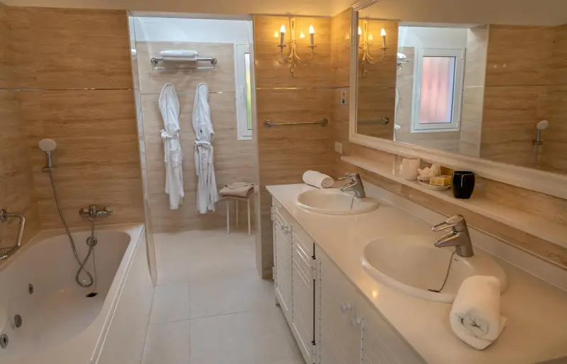 Une salle de bain lumineuse avec baignoire et deux vasques.