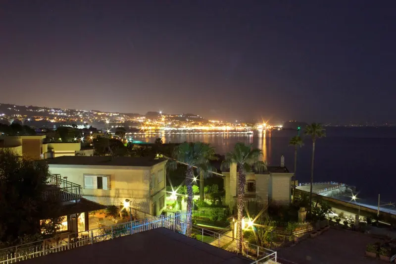 Vue nocturne sur une ville côtière illuminée et la mer.