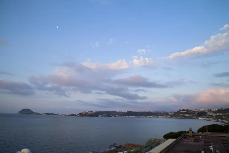 Un ciel nuageux au crépuscule surplombe une côte rocheuse et la mer.