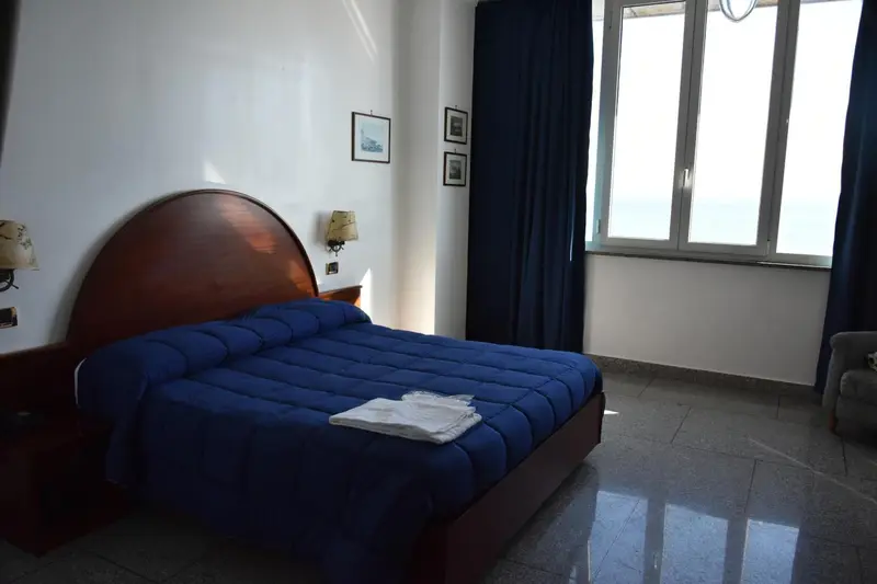 Une chambre lumineuse avec un grand lit recouvert d'une couverture bleue.