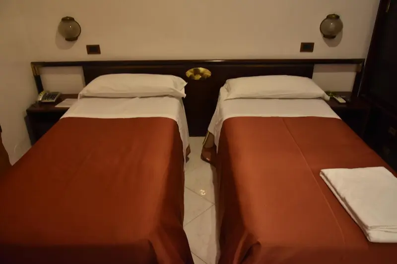 Deux lits simples dans une chambre aux murs beiges.