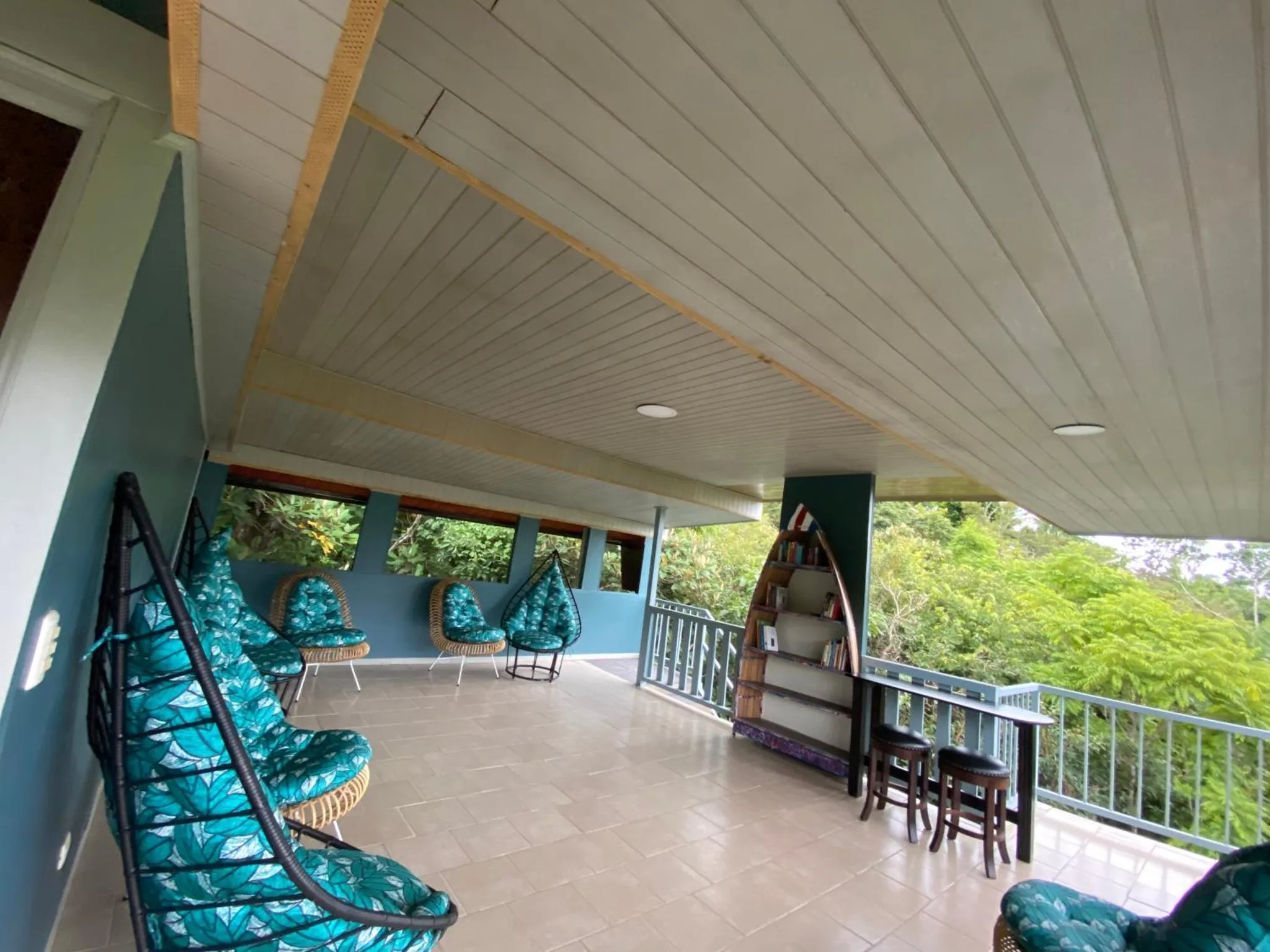 Terrasse ombragée avec mobilier d'extérieur et vue sur la végétation.
