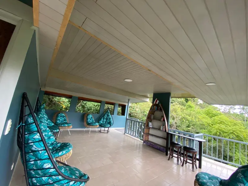 Terrasse ombragée avec mobilier d'extérieur et vue sur la végétation.