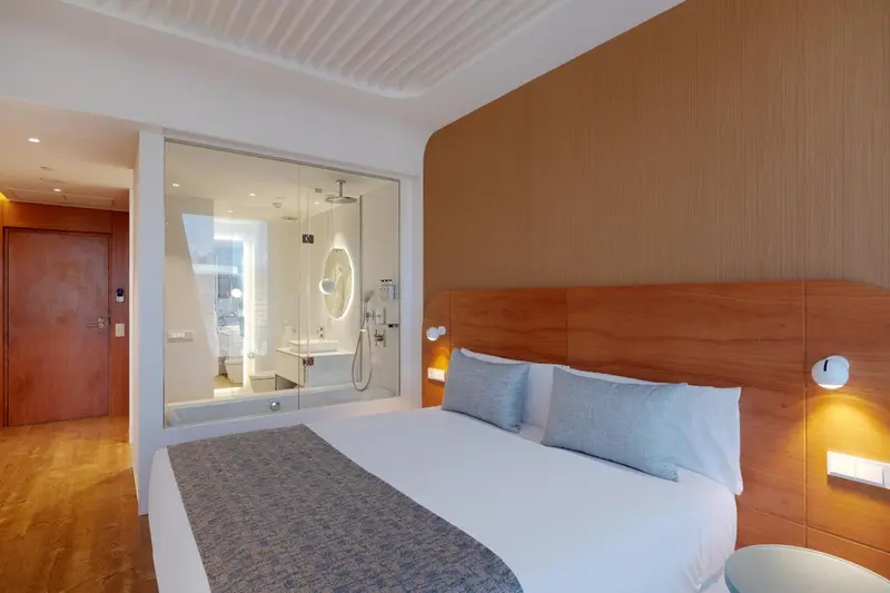Une chambre moderne avec un grand lit et une salle de bain vitrée.
