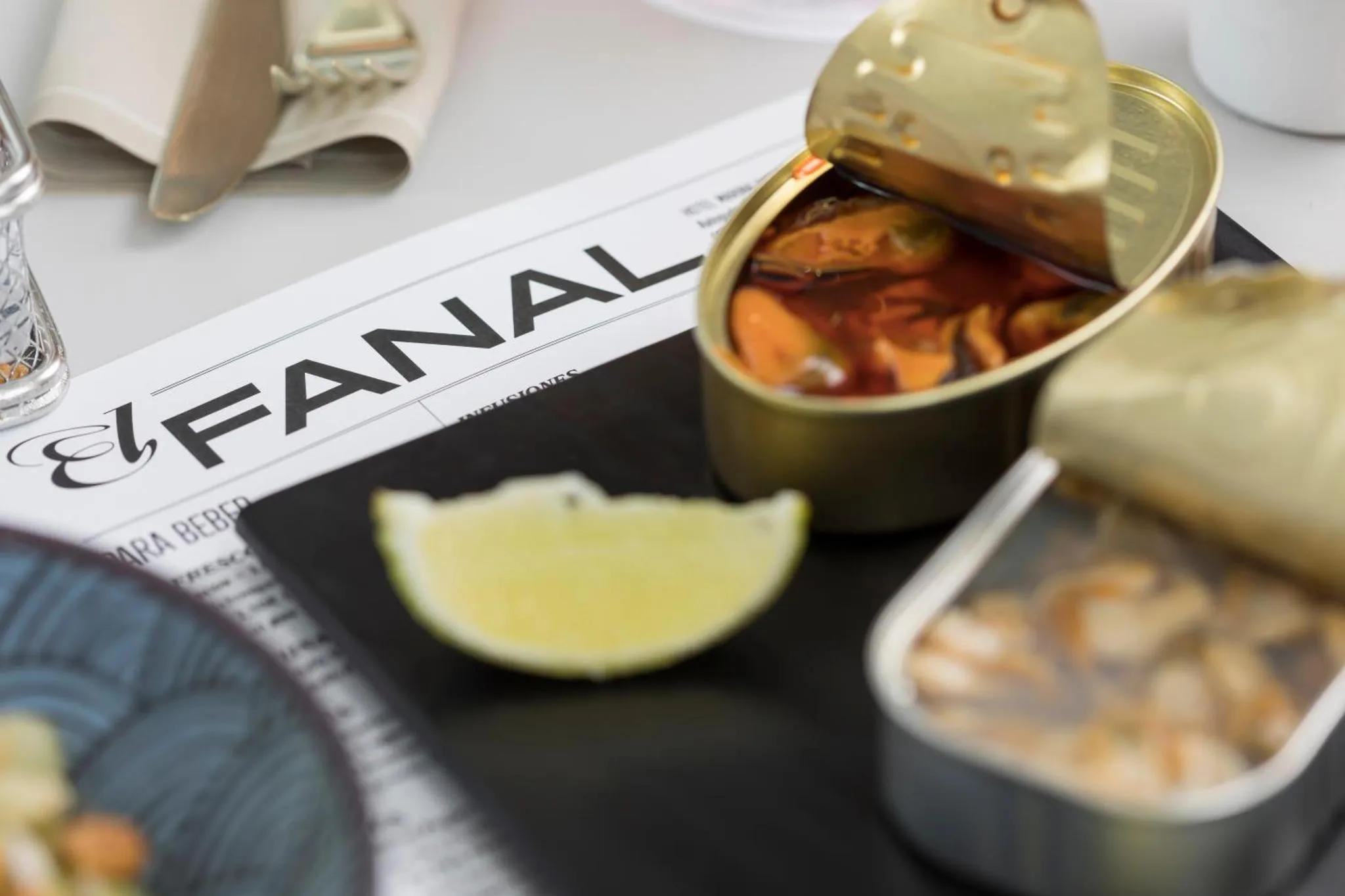 Une portion de fruits de mer en conserve est présentée avec une tranche de citron et un verre.