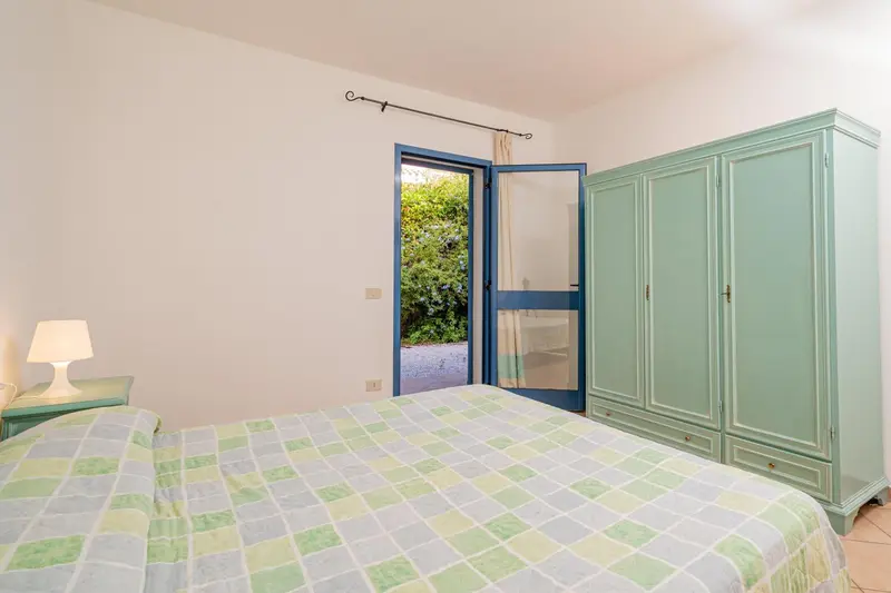 Une chambre lumineuse avec un lit recouvert d'une courtepointe et une armoire.