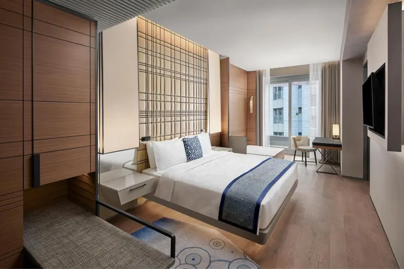 Une chambre moderne avec un grand lit et un bureau près d'une fenêtre.