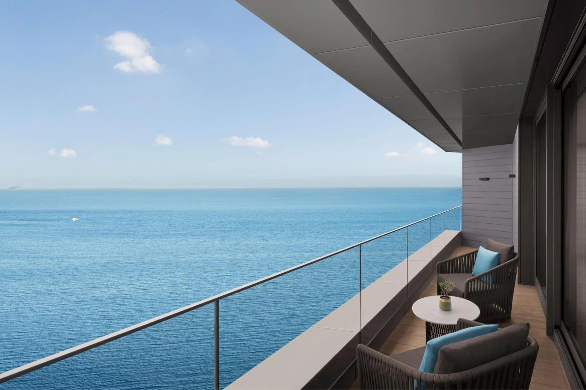 Vue sur la mer depuis une terrasse aménagée avec des fauteuils et une table basse.