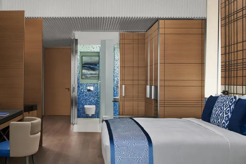 Une chambre lumineuse avec un lit fait et un espace douche vitré.