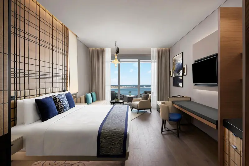 Chambre lumineuse avec un grand lit et une vue sur la mer.